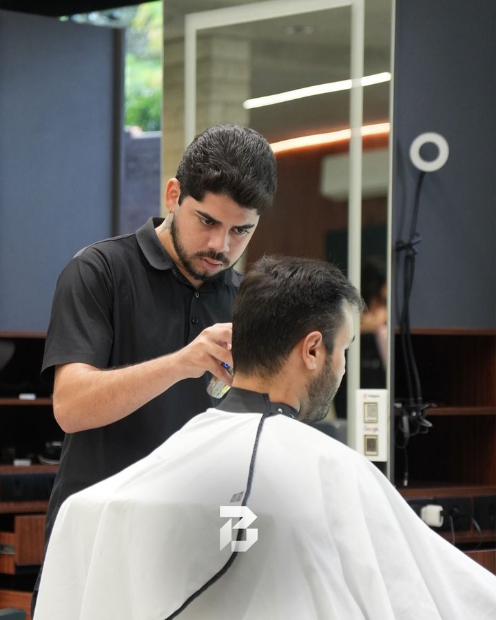 Barbeiro acertando a nuca de um cliente com a máquina