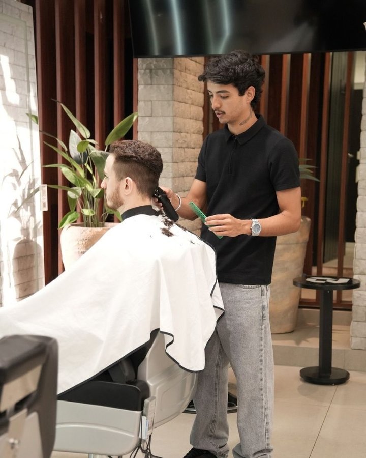 Barbeiro fazendo o degradê de um cliente no salão