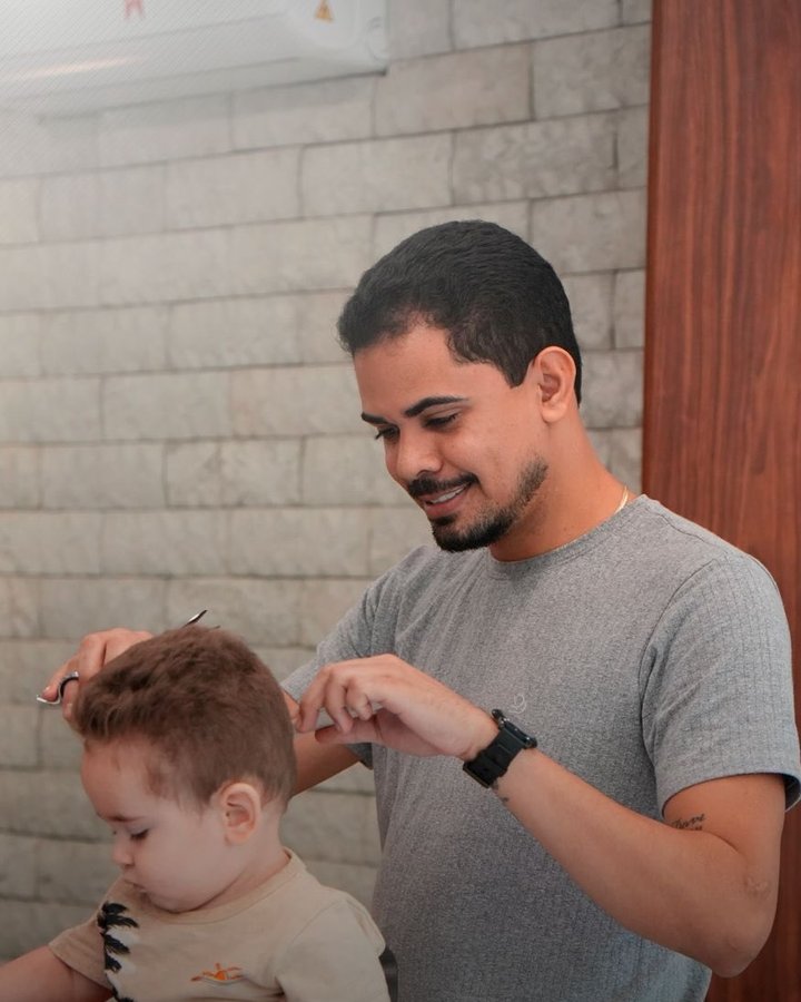 Barbeiro cortando o cabelo de uma criança no espaço kids